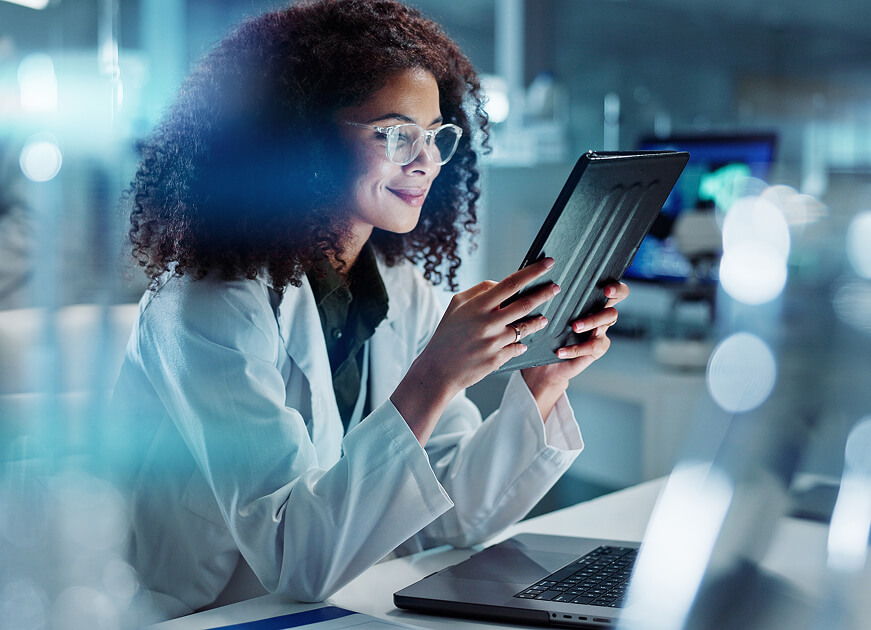 Healthcare researcher using a tablet in a lab, representing the healthcare sector among the industries we serve.