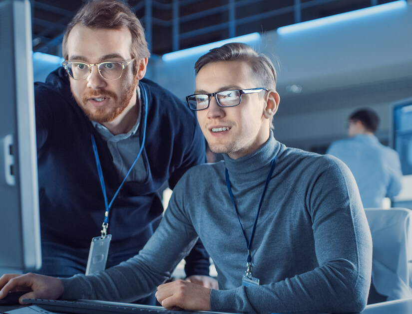 Two IT professionals collaborating at a computer, showcasing RevStar’s digital transformation services.