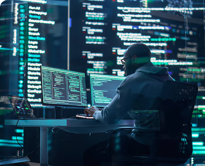 IT professional analyzing code on multiple monitors, representing the technology sector among the industries we serve.