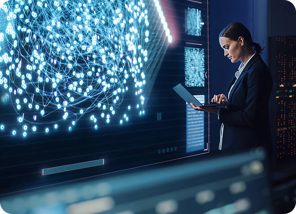 Business professional analyzing a large digital network visualization on a screen while working on a laptop.