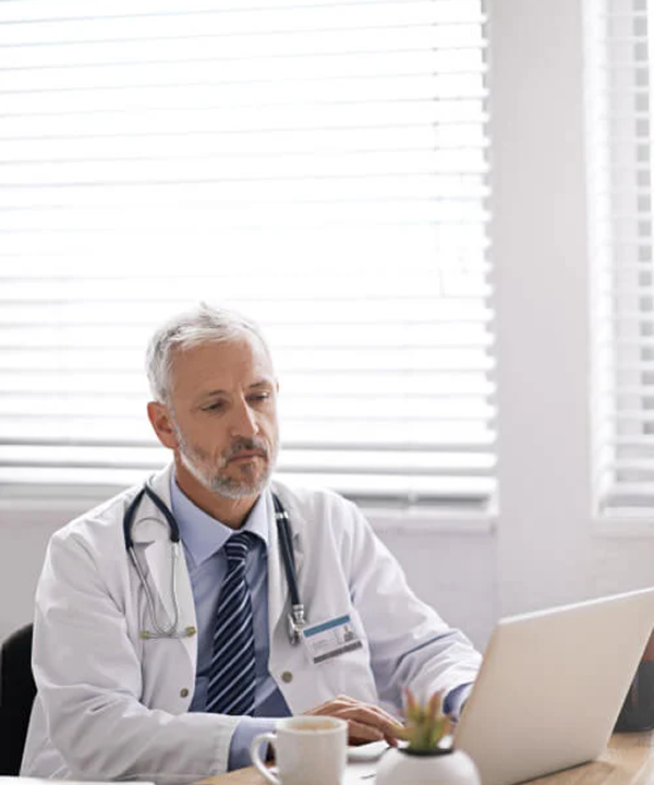 Medical professional in an office looking at a laptop.
