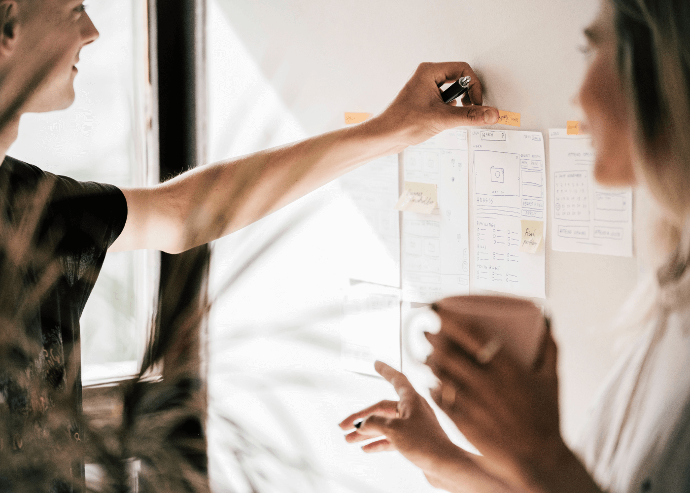 Two working professionals mapping out wireframes on wall