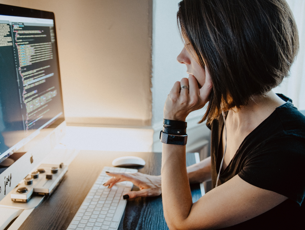 Short haired female developer inspecting code editor on desktop