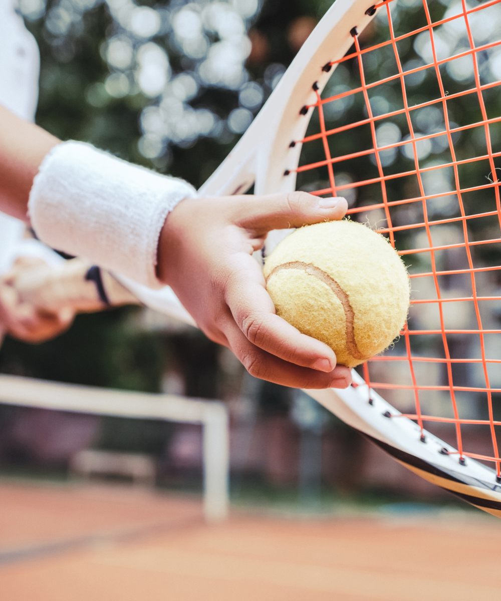 Close up of tennis player's hands holding tennis ball against racket